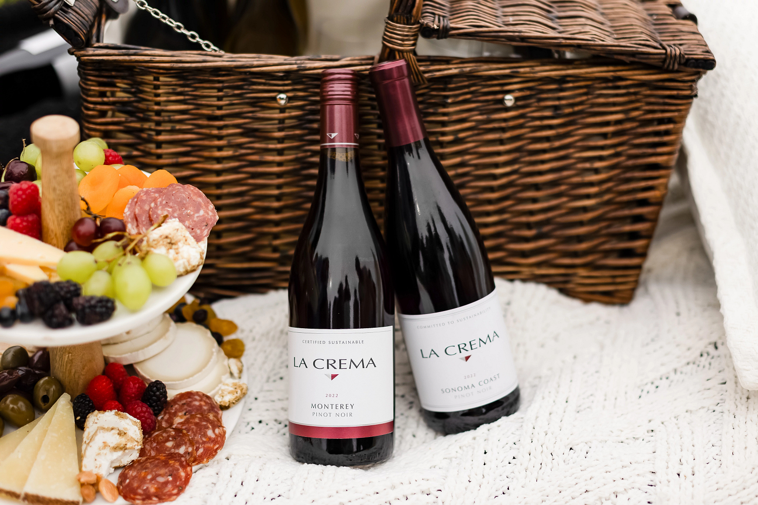 Two bottles of La Crema Pinot Noir at a picnic with food
